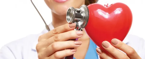 Doctor holding a stethescope to a plastic heart